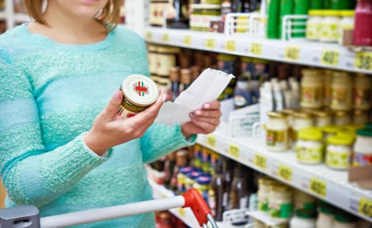 Mulher olhando para o fundo de uma lata no supermercado