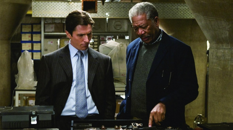 Bruce Wayne, de Christian Bale, consulta Lucius Fox, de Morgan Freeman, em um laboratório em Batman Begins