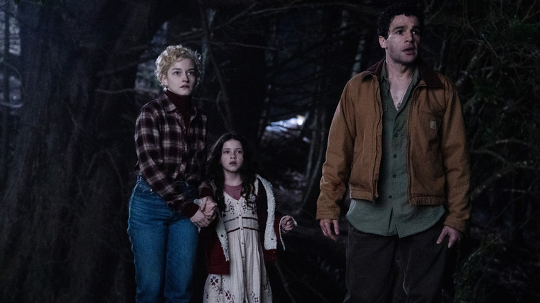 Julia Garner como Charlotte, Matilda Firth como Ginger e Christopher Abbott como Blake parecendo aterrorizado na floresta em Wolf Man