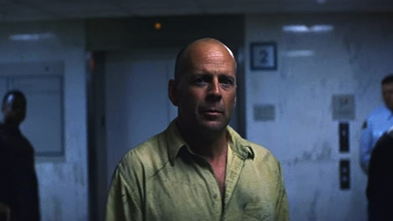 David Dunn parado em um hospital em Unbreakable, olhando para a câmera