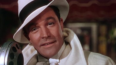 Gene Kelly como Donald Lockwood usando chapéu e casaco brancos em Cantando na Chuva