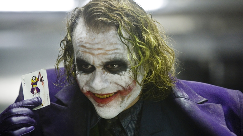 Heath Ledger como Coringa segurando uma carta de Coringa em O Cavaleiro das Trevas