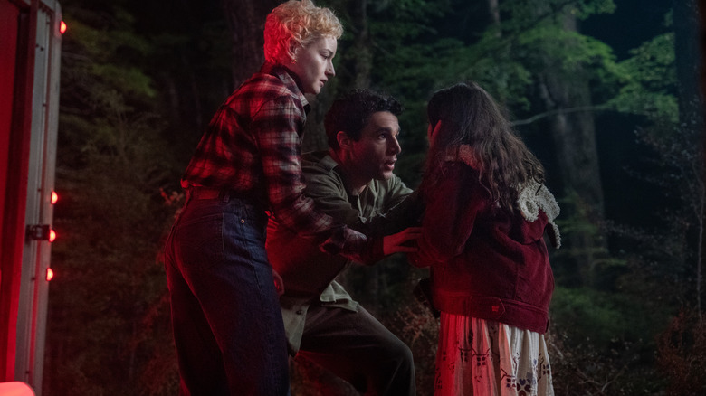 Christopher Abbott como Blake e Julia Garner como Charlotte acalmam sua filha Ginger (Matilda Firth) após um encontro traumático em Wolf Man