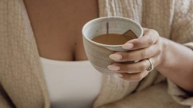 Mulher registrando no diário e tomando café.