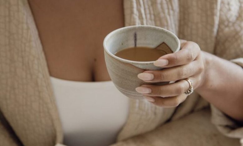 Mulher registrando no diário e tomando café.